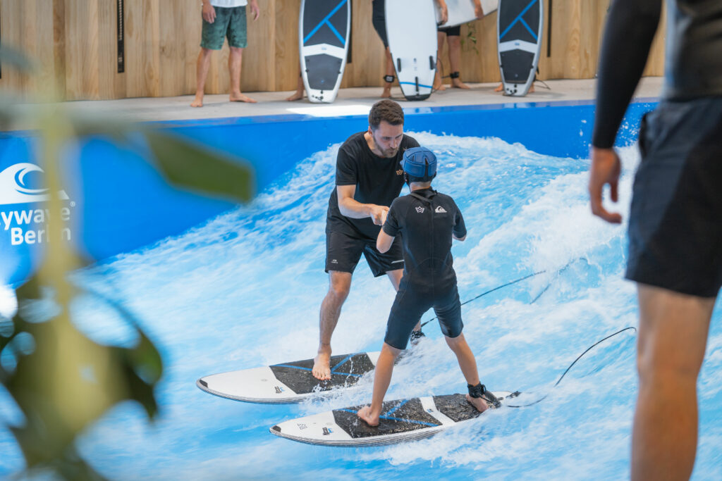 child surfs with surf coach