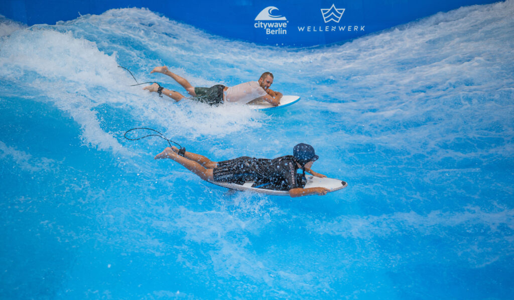 two surfers bodysurf on standing wave