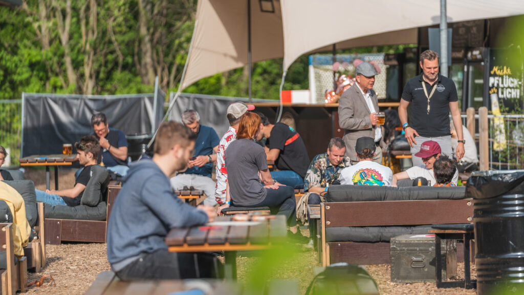 Menschen sitzen im Deus Biergarten
