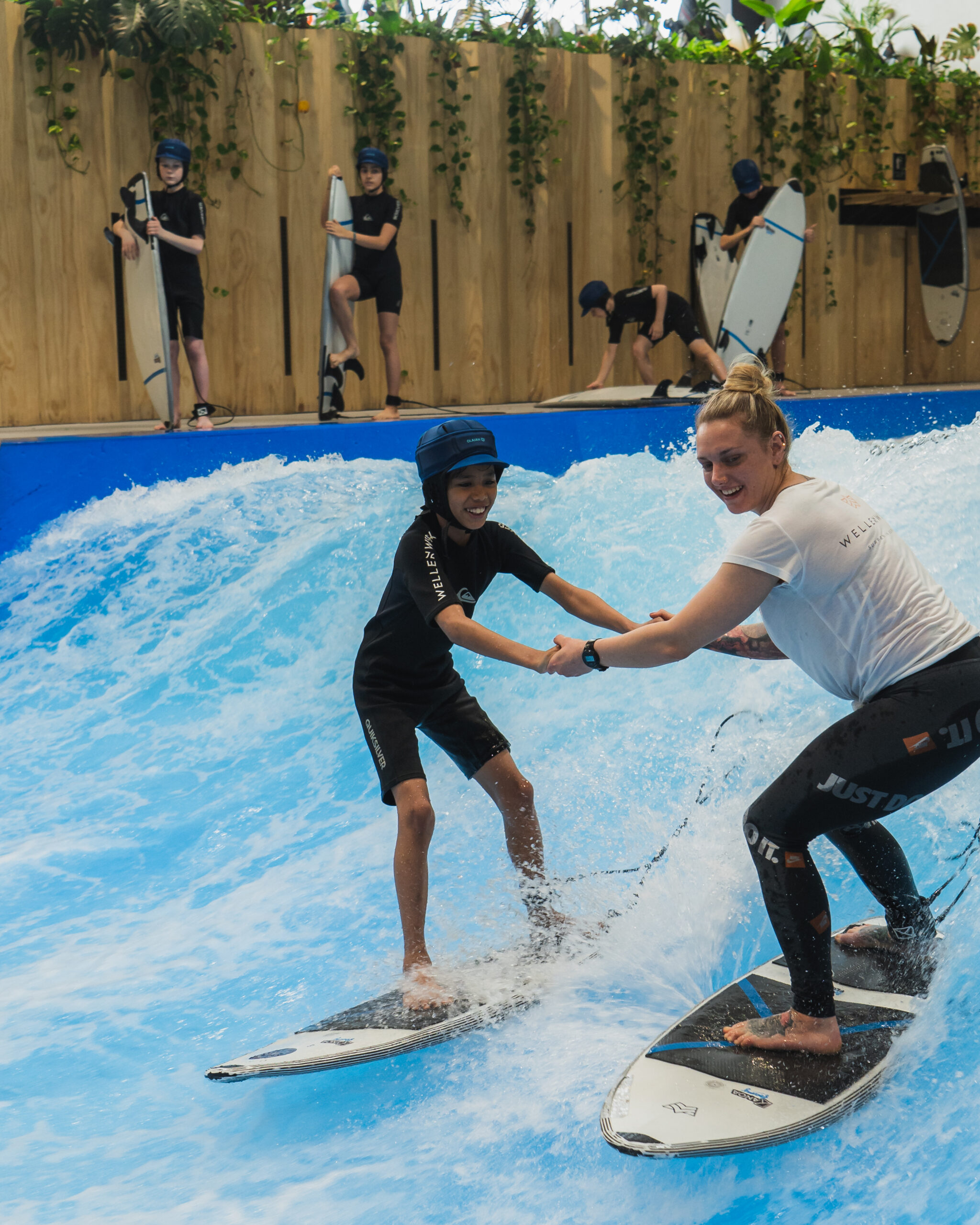 Eine Surflehrerin mit Kind beim Kids Surf Camp im Wellenwerk