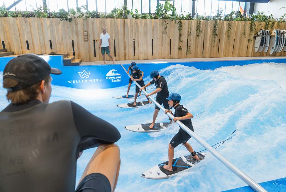 Kids-Camp-Gruppe übt gemeinsam mit Haltestange auf der Welle