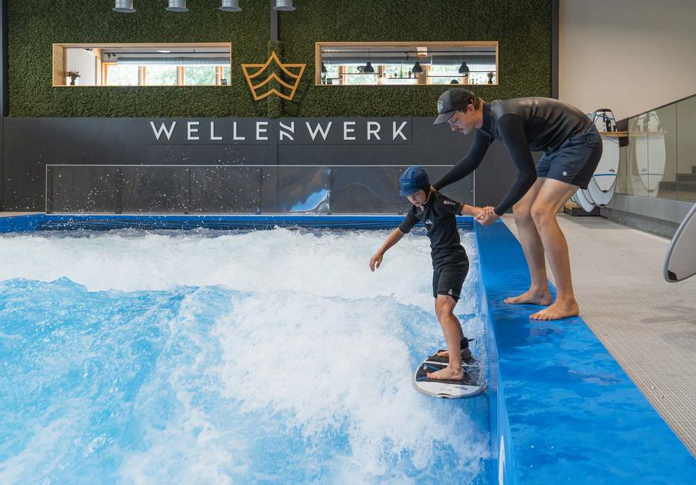 Kind steht mit Haltestange zum ersten Mal auf der stehenden Welle im Wellenwerk Berlin